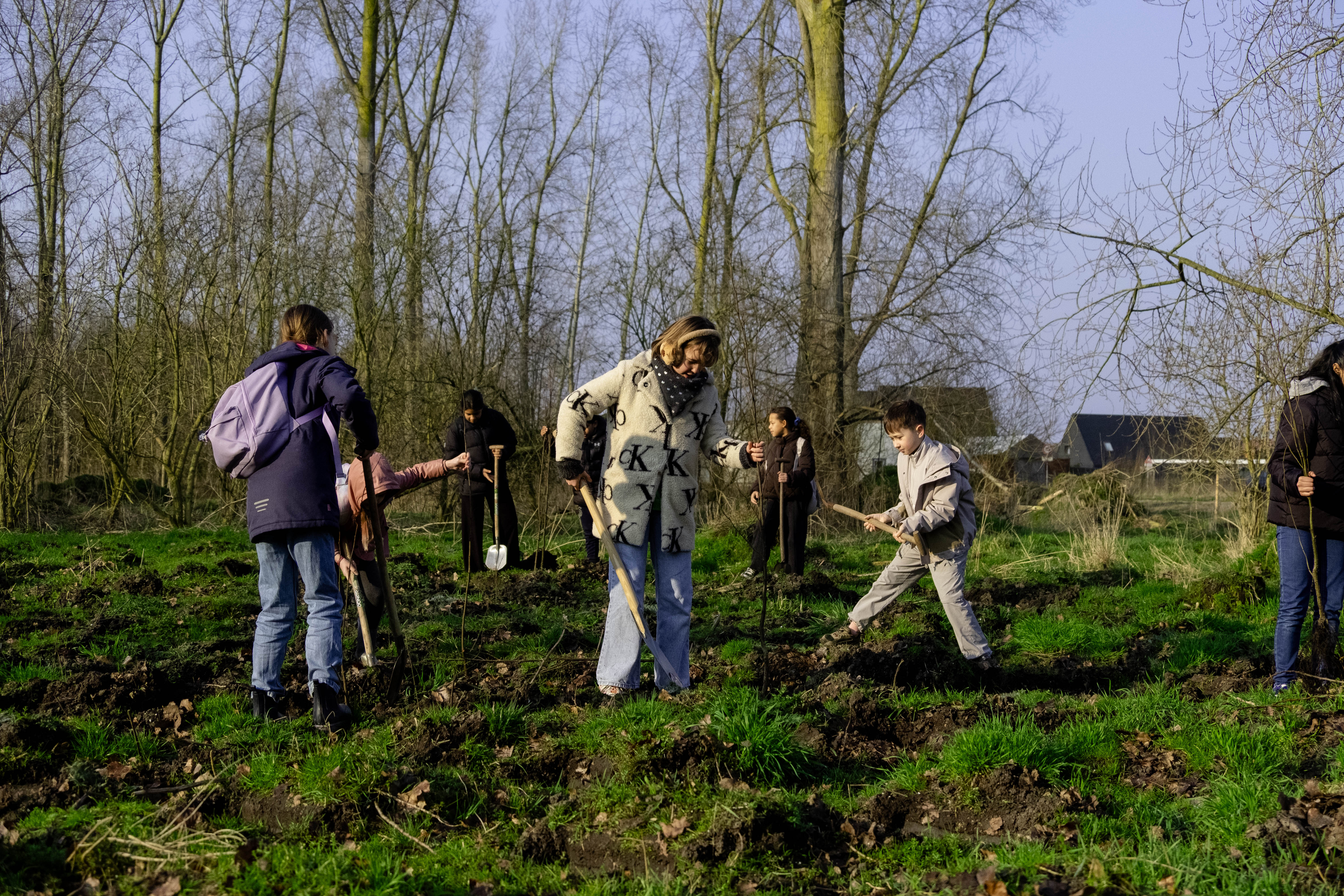 Almeerders planten samen jonge bomen in een groen veld bij Stad & Natuur